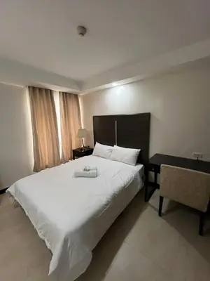 a bedroom with a large white bed and a desk at A Venue Residences 80N in Manila