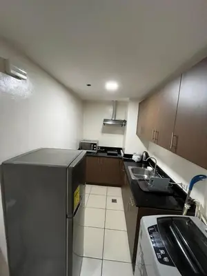 a small kitchen with a sink and a refrigerator at A Venue Residences 80N in Manila