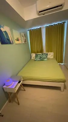 a bedroom with a green bed and a table at 2- Bedroom Condo in Metro Manila - Azure Beach in Manila