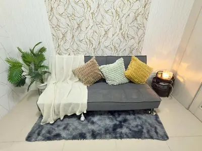 a couch with pillows and a rug in a room at Sea Affordable staycation in Manila