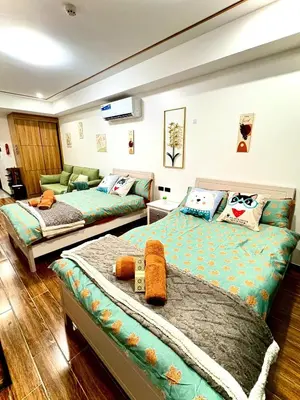 a bedroom with two beds and a couch at Sybay Suites twin double bed beside Okada near T3 MOA NAIA Ayala MSV1517H in Manila