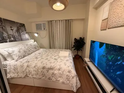 a bedroom with a bed and a flat screen tv at 1BR Luxury Apartment The Camden Place in Manila