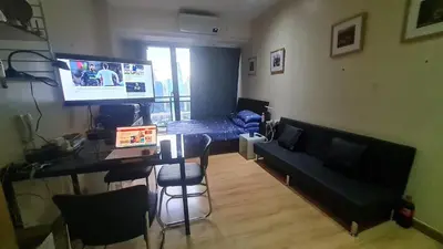 a living room with a table and a television and a couch at The Oasis in Knigthsbridge Residence, Makati in Manila