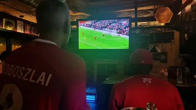 a man in a bar watching a soccer game on a television at The Oasis in Knigthsbridge Residence, Makati in Manila