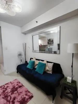 a living room with a couch and a mirror at Sea Residences Mall of Asia in Manila
