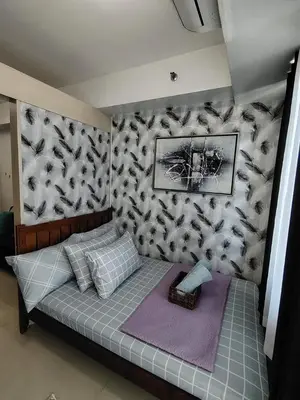 a bed in a room with a wall at Sea Residences Mall of Asia in Manila