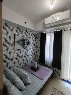 a bed in a room with a wall at Sea Residences Mall of Asia in Manila