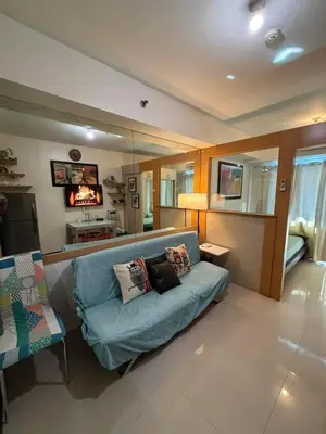a living room with a blue couch with pillows on it at Sea Residences Mall of Asia in Manila