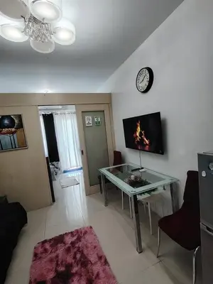a living room with a glass table and a clock at Sea Residences Mall of Asia in Manila