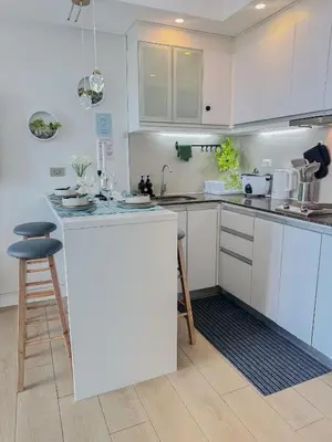 a kitchen with white cabinets and a bar with a stool at nJoy! Tropical Breeze at Venice Grand Canal in Manila
