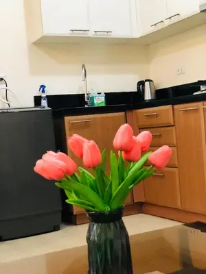 a vase with red flowers in a kitchen at Charming 1BR with Balcony near Venice mall&BGC in Manila