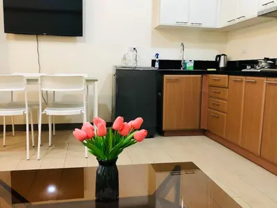 a kitchen with a vase with red flowers on a table at Charming 1BR with Balcony near Venice mall&BGC in Manila