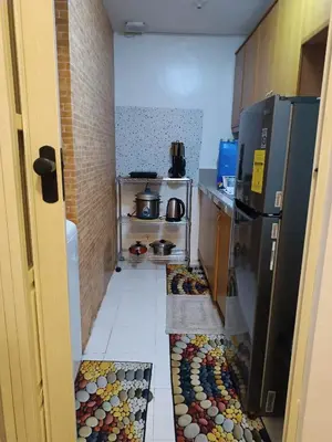 a small kitchen with a tile floor and a refrigerator at Althea's Homestay at Forebeswood Height in Manila