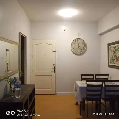 a dining room with a table and a clock on the wall at Althea's Homestay at Forebeswood Height in Manila