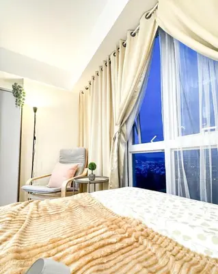 a bedroom with a large window and a bed and a chair at Kasara Urban Resort Residences by Amari Staycations in Manila