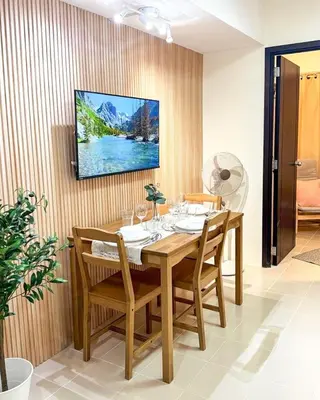 a dining room with a table and a tv on a wall at Kasara Urban Resort Residences by Amari Staycations in Manila