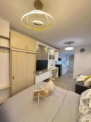 a bedroom with a large bed and a living room at Shell Residences Mall of Asia Caitlin's Place in Manila