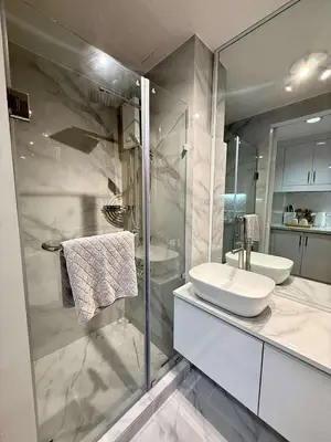 a bathroom with a glass shower and a sink at Shell Residences Mall of Asia Caitlin's Place in Manila