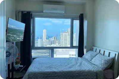 a bedroom with a bed and a large window at Cosy Makati Penthouse Studio with Great View in Manila