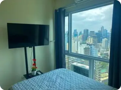 a bedroom with a bed and a large window at Cosy Makati Penthouse Studio with Great View in Manila