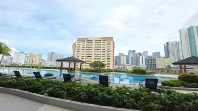 a swimming pool with chairs and a city skyline at Cosy Makati Penthouse Studio with Great View in Manila