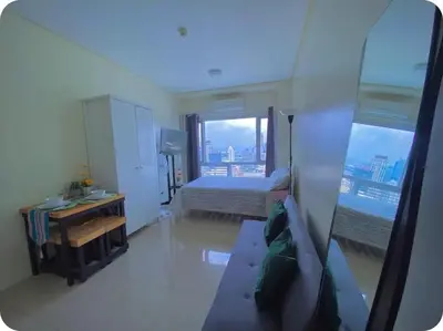 a bedroom with a bed and a desk and a window at Cosy Makati Penthouse Studio with Great View in Manila