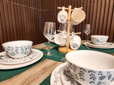a wooden table with plates and cups and wine glasses at Amazing Poolside 1br MOA Netflix 100mbps fiber in Manila