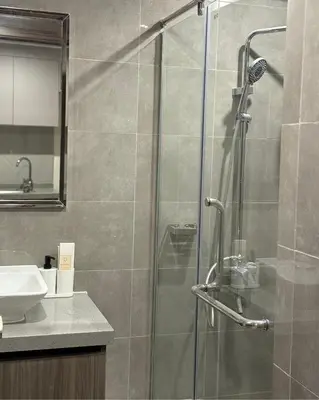 a bathroom with a glass shower with a sink at Bruné - Parañaque in Manila