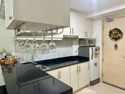 a kitchen with white cabinets and a black counter top at AMD Staycation in Manila