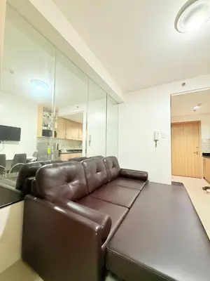 a living room with a brown leather couch in a room at Dreamstaycation shore residences in Manila