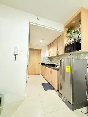 a kitchen with a stainless steel refrigerator and wooden cabinets at Dreamstaycation shore residences in Manila