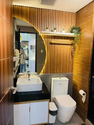 a man taking a picture of a bathroom with a toilet and sink at 19s CAI in Manila