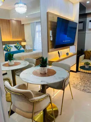 a hotel room with two tables and a bed and a tv at 19s CAI in Manila