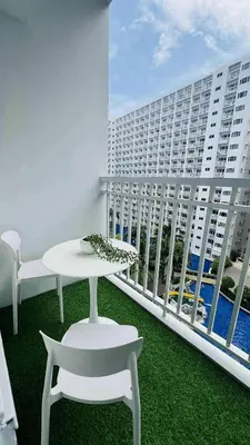 a balcony with a table and chairs and a large building at Kaizen Pod - Shore Residences Staycation, MOA Complex, Near airport in Manila