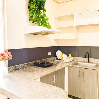 a kitchen with white cabinets and a plant on the wall at Birch Tower Ocean View Unit in Manila