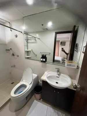 a bathroom with a toilet and a sink and a mirror at A Venue Residences 80G in Manila