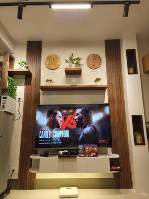 a flat screen tv on a wall with two clocks at Entire unit 1 Bedroom with City View - Paul Riley's Pad in Manila