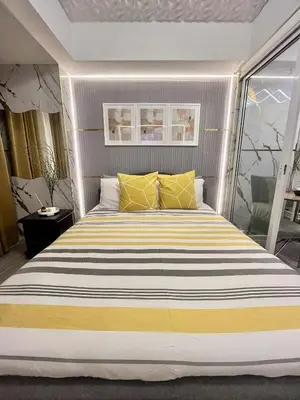 a bedroom with a large bed with yellow pillows at Urban Retreat at Azure in Manila