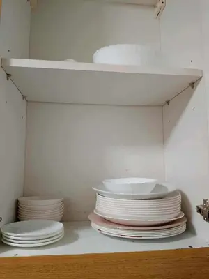 a stack of plates sitting on a shelf in a kitchen at Family Suites 4 Shell Condo MOA 653B in Manila