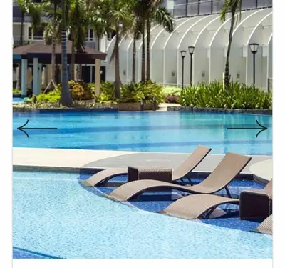 a swimming pool with two lounge chairs in a resort at Family Suites 4 Shell Condo MOA 653B in Manila