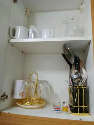a kitchen shelf with cups and utensils on it at Family Suites 4 Shell Condo MOA 653B in Manila