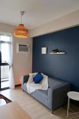 a couch in a living room with a blue wall at Bright & Cozy Condo Near Okada 2 mins walk in Manila