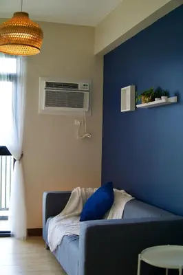 a living room with a couch and a blue wall at Bright & Cozy Condo Near Okada 2 mins walk in Manila