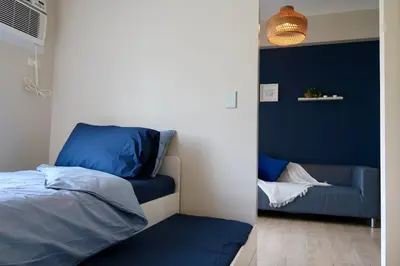 a bedroom with blue walls and a bed and a couch at Bright & Cozy Condo Near Okada 2 mins walk in Manila