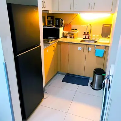 a small kitchen with a black refrigerator and a sink at Cozy Modernistic 1 BR with Veranda! in Manila