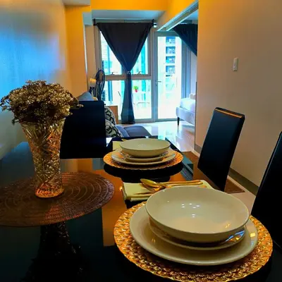 a dining room table with plates and a vase of flowers at Cozy Modernistic 1 BR with Veranda! in Manila
