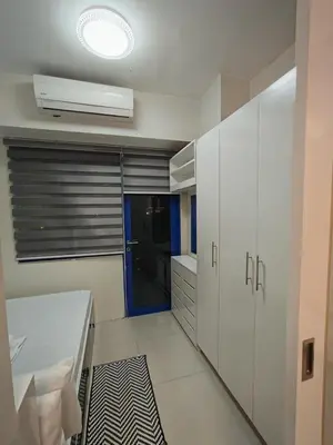a kitchen with white cabinets and a ceiling fan at Sea residences MOA-MR in Manila