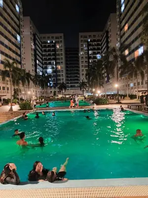 a group of people swimming in a pool at night at Sea residences MOA-MR in Manila