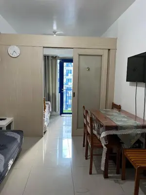 a dining room with a table and chairs and a tv at Sea Residences Vertex in Manila