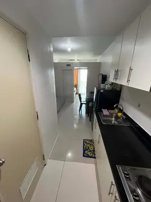 a small kitchen with white cabinets and a table at Sea Residences Vertex in Manila
